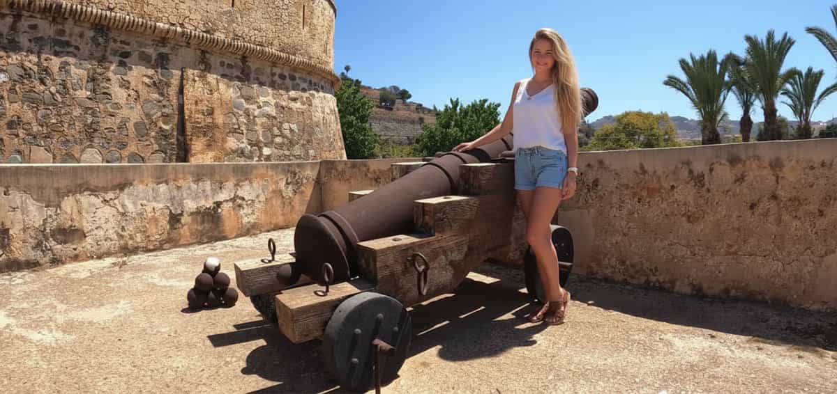 Femme posant à côté d’un canon défensif au Castillo de La Herradura avec vue sur la côte